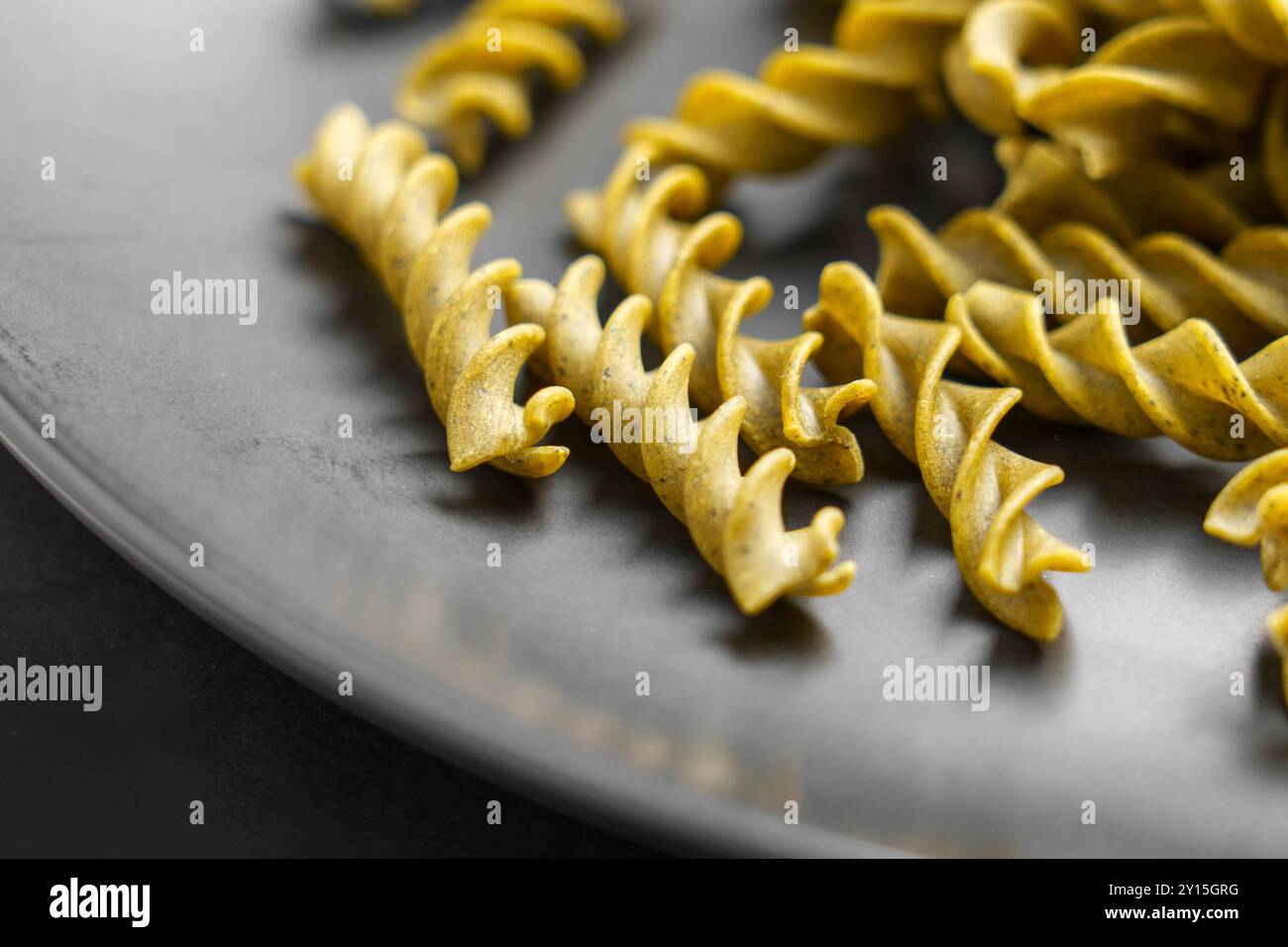 Bio einzigartige grüne Pasta für gesundheitsbewusste Lebensmittelliebhaber auf einem grauen Teller Nahaufnahme. Glutenfreie Zutaten Stockfoto