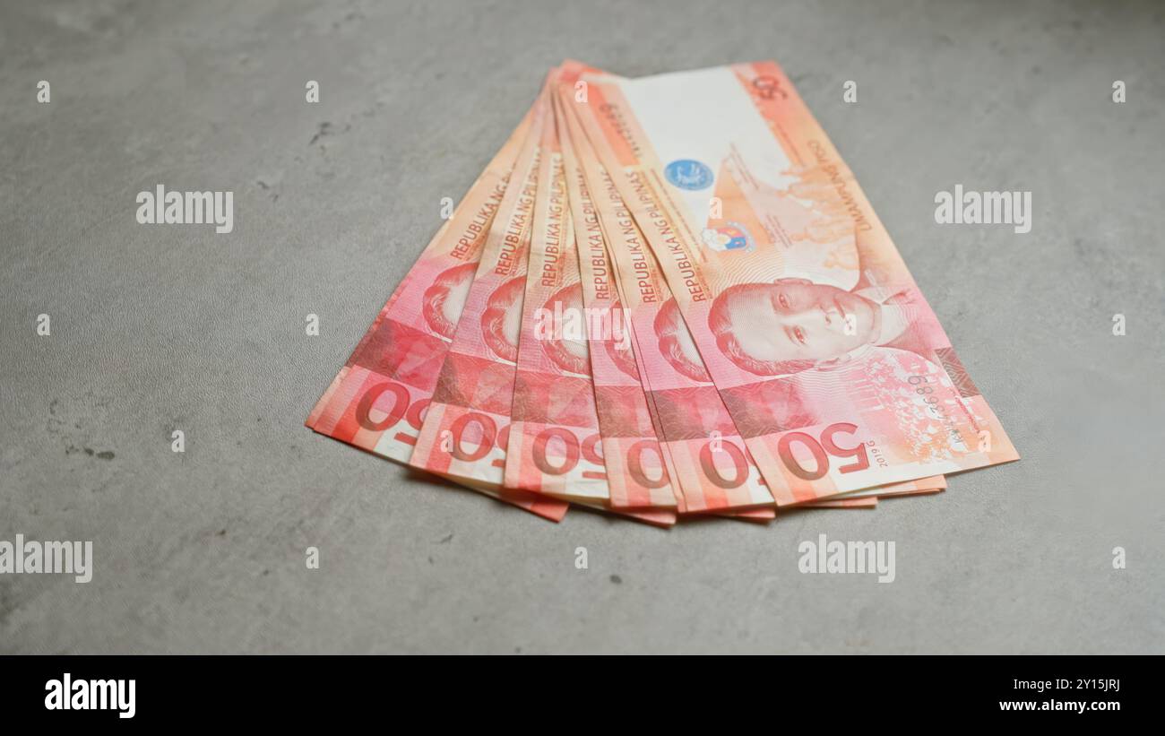 Philippinische Peso-Banknoten, die ordentlich auf einer Betonoberfläche angeordnet sind und farbenfrohe Geldscheine in flacher Lage darstellen. Stockfoto