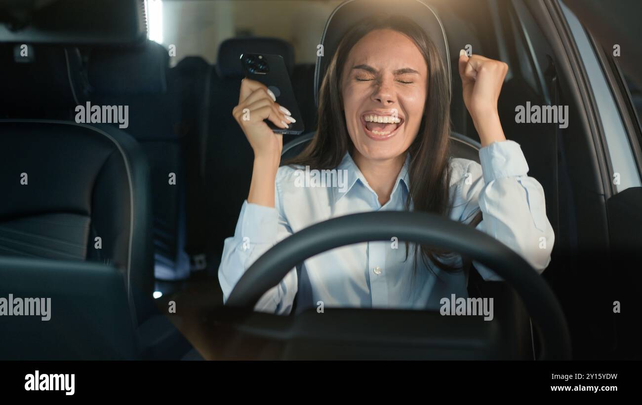Kaukasische Geschäftsfrau glücklich aufgeregtes Mädchen Geschäftsfrau erfolgreiche Gewinnerin weibliche Fahrerin im Auto Auto Auto gewinnen Handy Erfolg Erfolg Erfolg Erfolg Erfolg Stockfoto