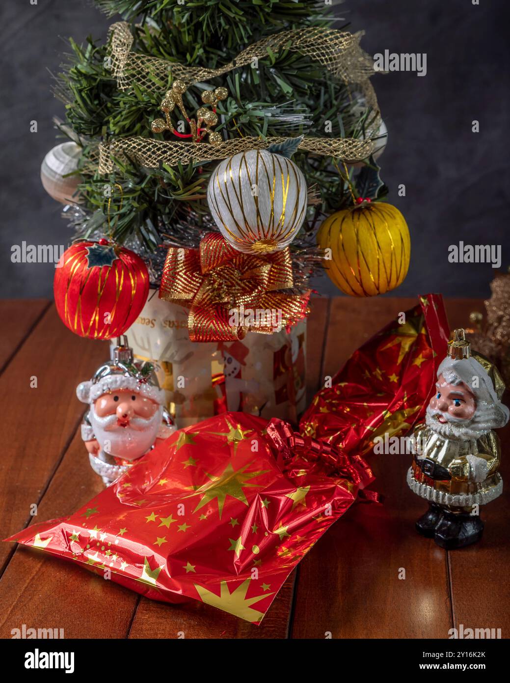 Nahaufnahme eines kleinen, geschmückten Weihnachtsbaums mit einem Geschenk und Weihnachtsmannfiguren darunter Stockfoto