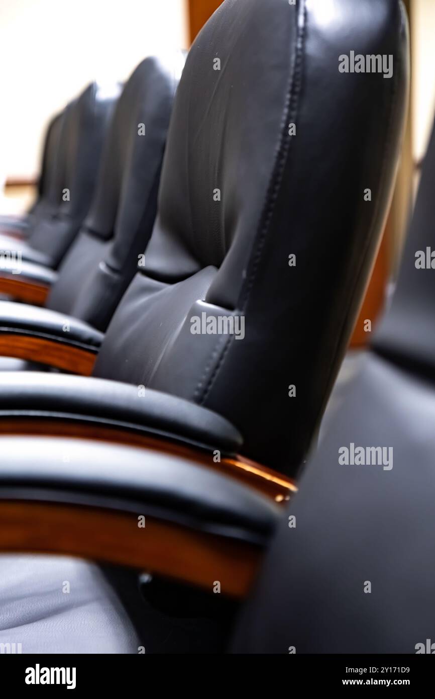 Reihe schwarzer Ledersessel, die sich am Executive Meeting Table im modernen Konferenzraum befinden Stockfoto