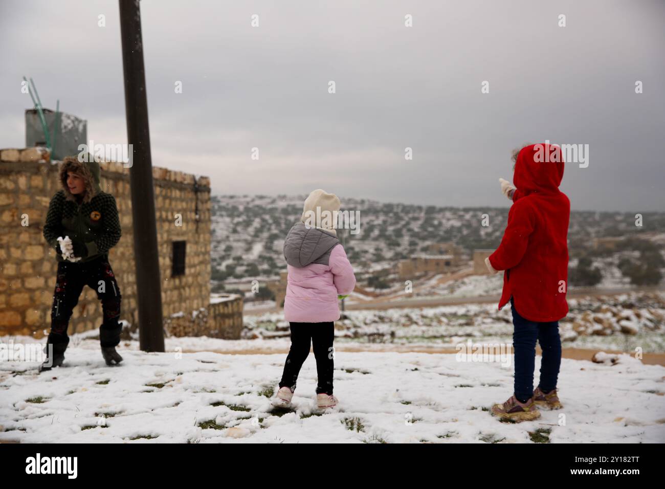 Aleppo, Syrien. Februar 2023. Syrische Kinder spielen im Schnee in Taqad, in der westlichen Aleppo-Landschaft. Die Landschaft Aleppos und das Gouvernement Idlib waren von eisigen Temperaturen betroffen und von einer Schneedecke bedeckt, nachdem die Luft in der Region einbrach. Die Witterungsbedingungen haben die vielen Vertriebenen in Nordwest-Syrien noch stärker verwundbar gemacht Stockfoto