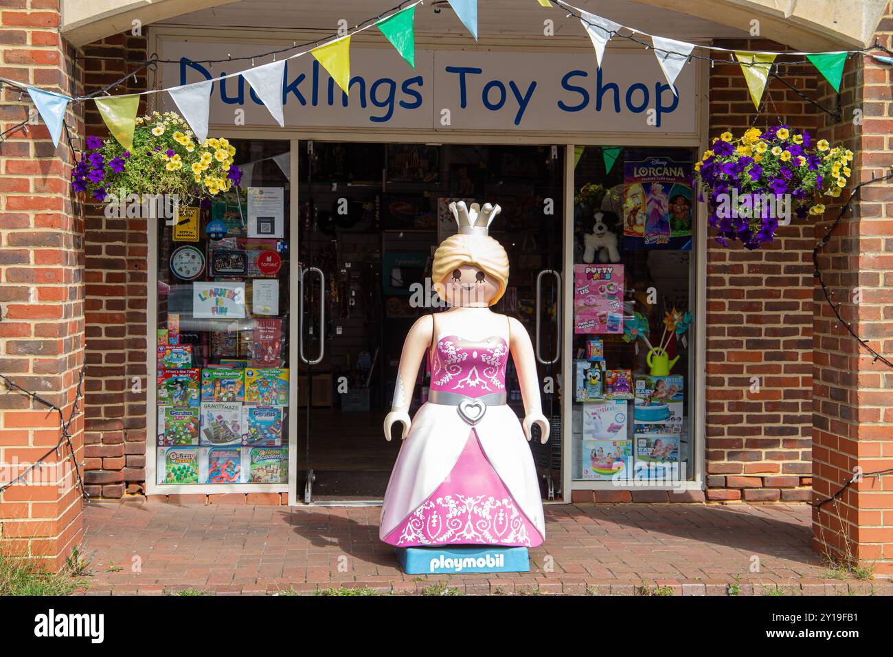 Vorderansicht des Eingangs des Toy Shop für Ententchen in Marlborough mit einer großen Playmobil Prinzessin, die draußen steht und darüber farbenfrohe Dekorationsfahnen. Stockfoto