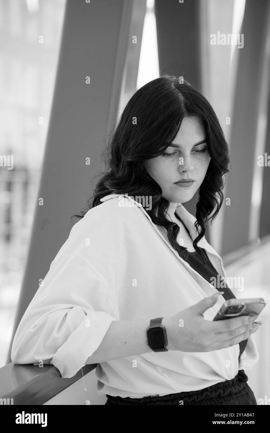 Kontemplative Geschäftsfrau, die sich in Modern Office mit mobiler Kommunikation beschäftigt. Stockfoto