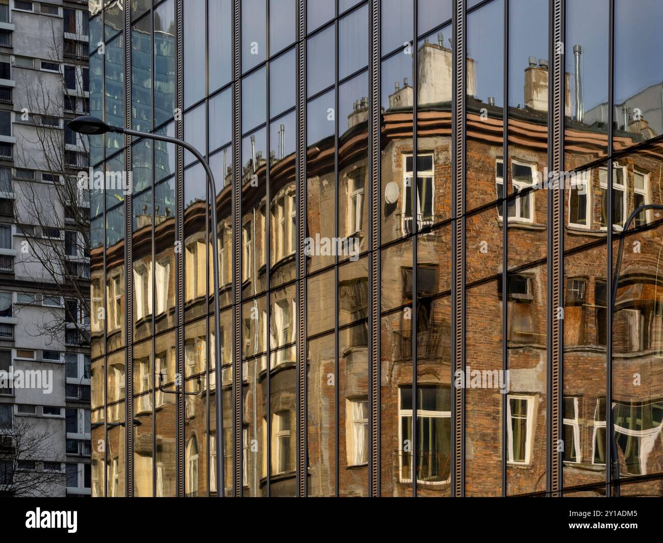 Ein Spiegelbild eines alten Mietshauses in der Glasfassade eines modernen Bürogebäudes. Stockfoto