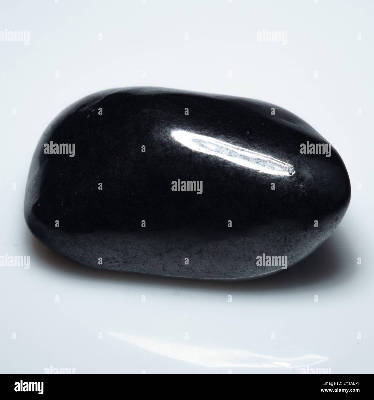 Polierte Eleganz: Shungite-Edelstein auf makellosem weißem Hintergrund. Stockfoto