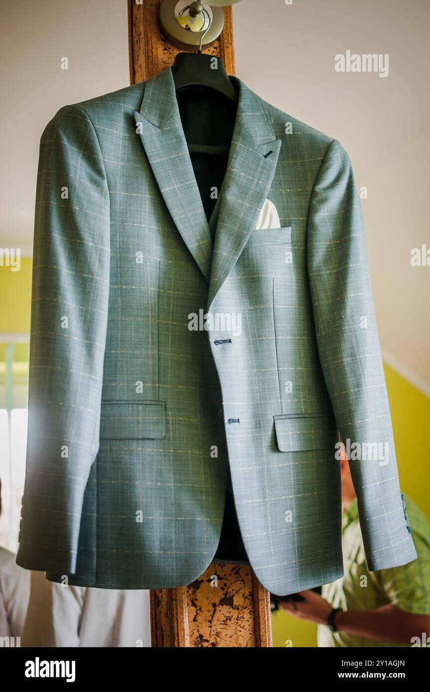 Elegantes, grün kariertes Sakko am Holzbügel im hellen Zimmer. Stockfoto