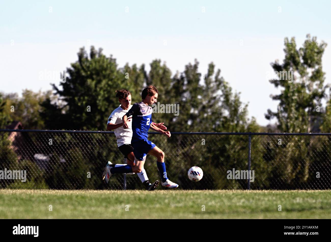 Illinois, USA. Stürmer und Verteidiger verfolgen den Ball während eines Highschool-Fußballspiels an einer Seitenlinie. Stockfoto