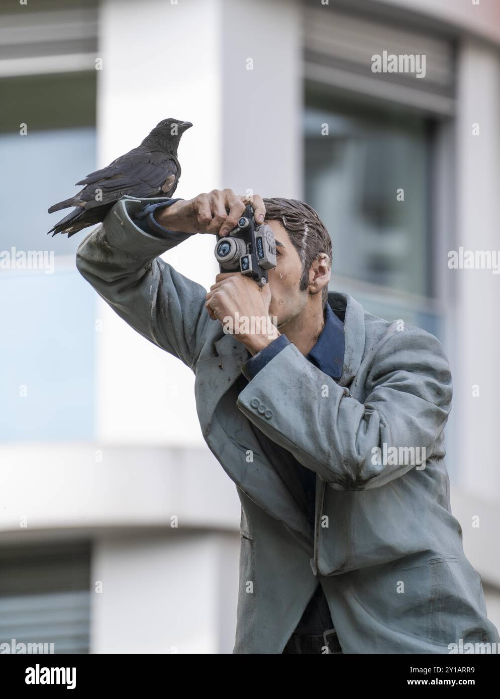 Echte Krähe auf einem Säulen-heiligen, der Fotograf, vor dem Hauptbahnhof in Düsseldorf, eine von 10 realistischen, lebensgroßen Skulpturen von Menschen Stockfoto