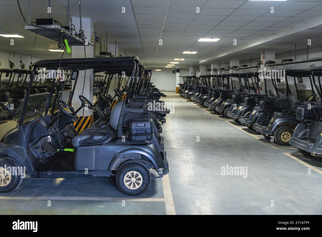 Horizontales Foto einer Reihe von Golfwagen, die in einer Garage geparkt sind Stockfoto