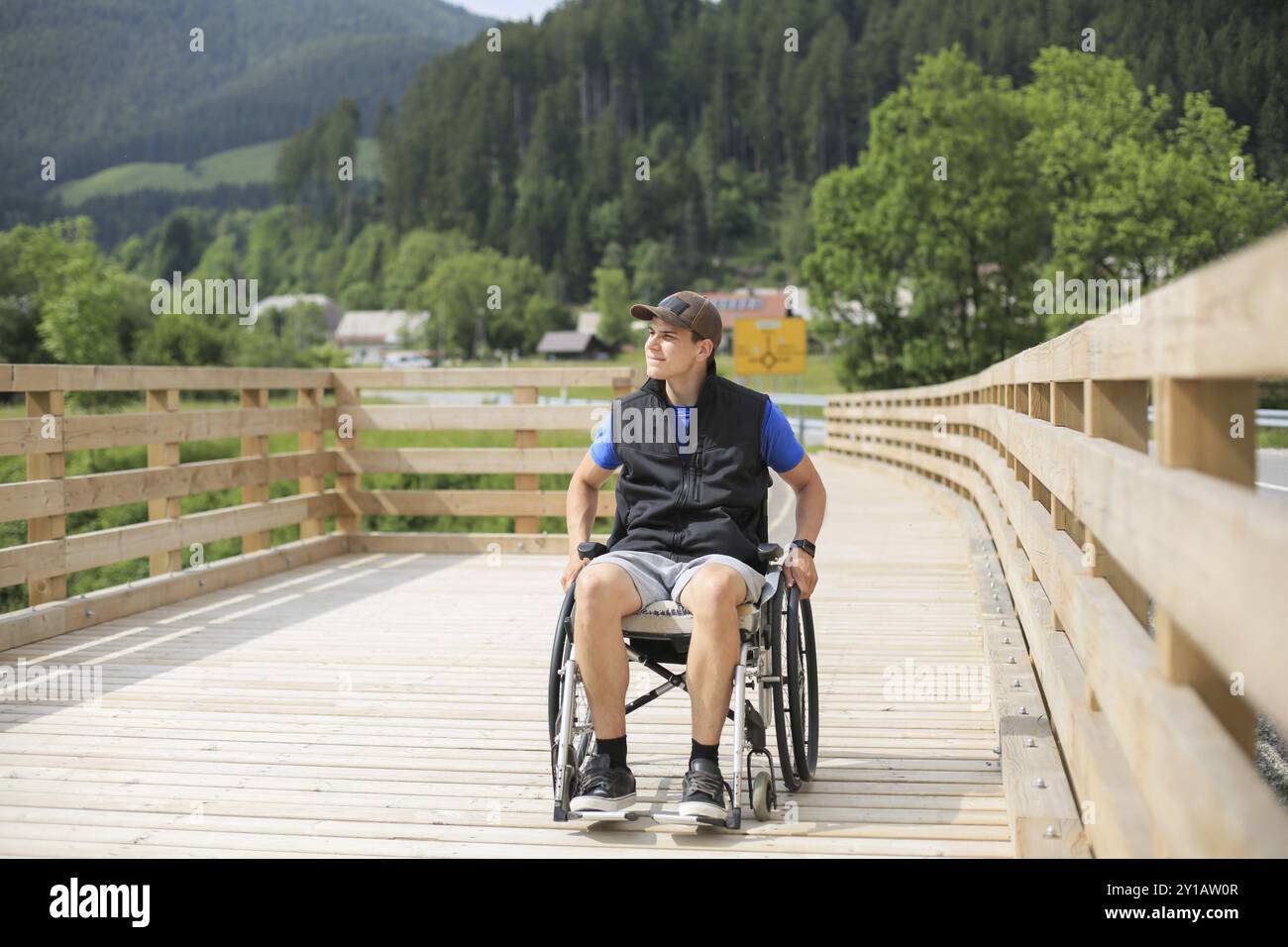 Behinderte junge Menschen auf einen Rollstuhl auf einer hölzernen Brücke weg Genießen in der Natur schöne Aussicht suchen Stockfoto