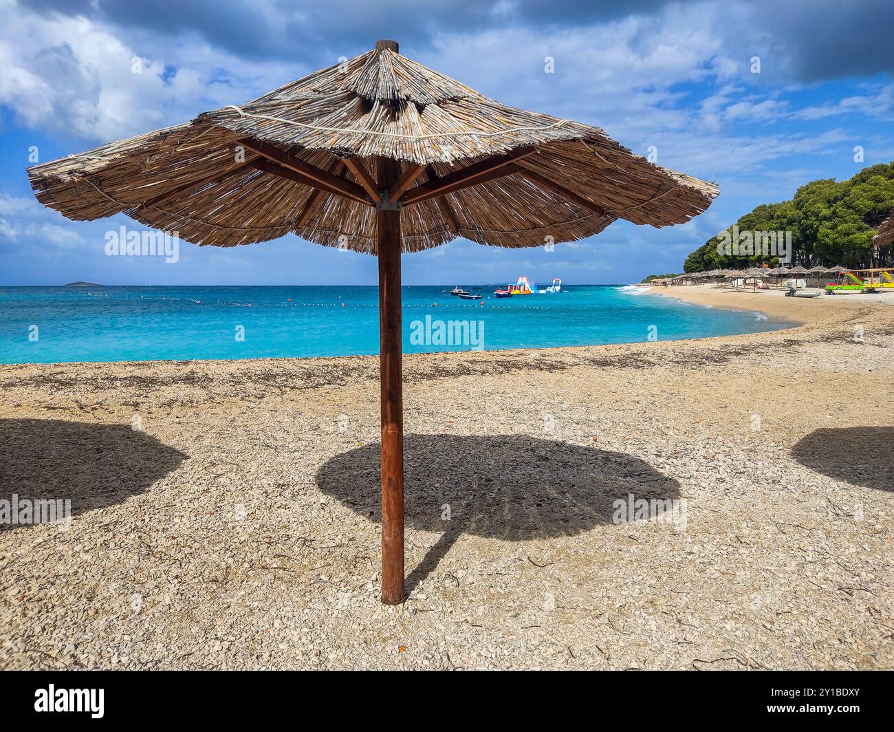 Primosten, Kroatien - Sonnenschirm am Schilf auf der Halbinsel Primosten mit türkisfarbenem Adria-Wasser, Wasserspielplatz an einem sonnigen Sommertag mit Stockfoto