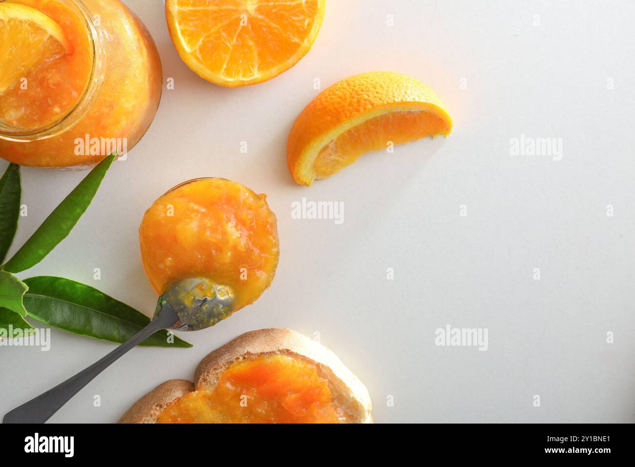 Gläser mit Orangenmarmelade isoliert auf weißem Tisch mit Früchten und Blättern. Draufsicht. Stockfoto