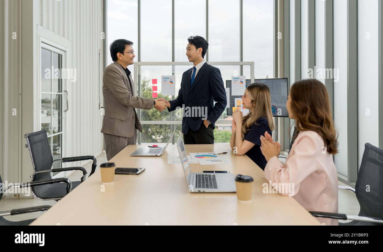 Firmenprofi in formeller Kleidung, die während eines Meetings in einem gut beleuchteten Bürobereich einen Handschlag erfährt. Stockfoto