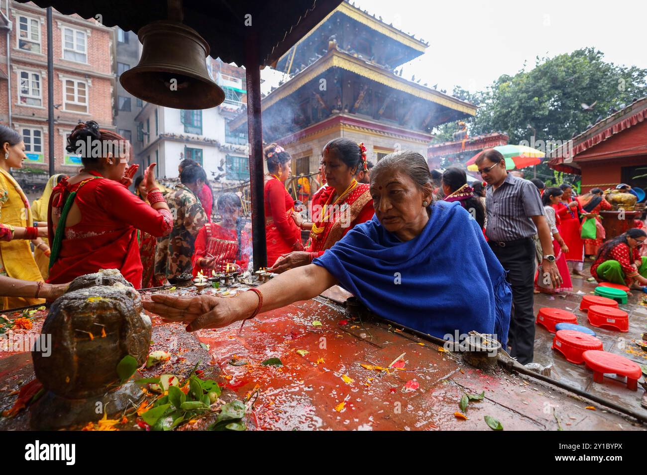 Eine nepalesische Hindu-Frau führt Rituale in einem Shiva-Tempel in Kathmandu, Nepal, am 6. August 2024, am Tag des Teej, durch. Nach der Tradition beobachten Frauen an diesem dritten Tag der dunklen Hälfte des Mondmonats, der in den nepalesischen Monat Bhadra fällt, Fasten und wünschen sich ein wohlhabendes Leben während der Beobachtung des Festivals. Laut der „Skanda Puran“ (eine religiöse Schrift der Hindus) erhält dieses Festival den Namen „Haritalika Teej“, da es genau an diesem Tag in der „Satya Yug“ (goldene Epoche der Wahrheit) ist, dass die Tochter des Himalaya, Parvati, von ihren Mägden versteckt wird, weil sie sich weigert, Lo zu heiraten Stockfoto