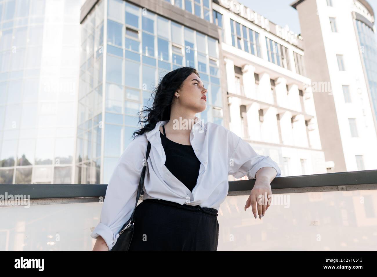 Selbstbewusste urbane Frau in eleganter Kleidung gegen moderne Architektur. Stockfoto