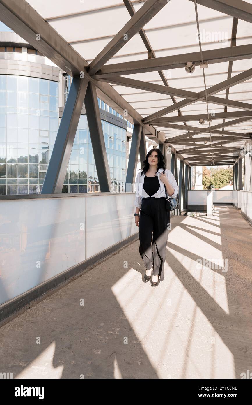 Geschäftsfrau, die selbstbewusst auf einer modernen Glasbrücke läuft. Stockfoto