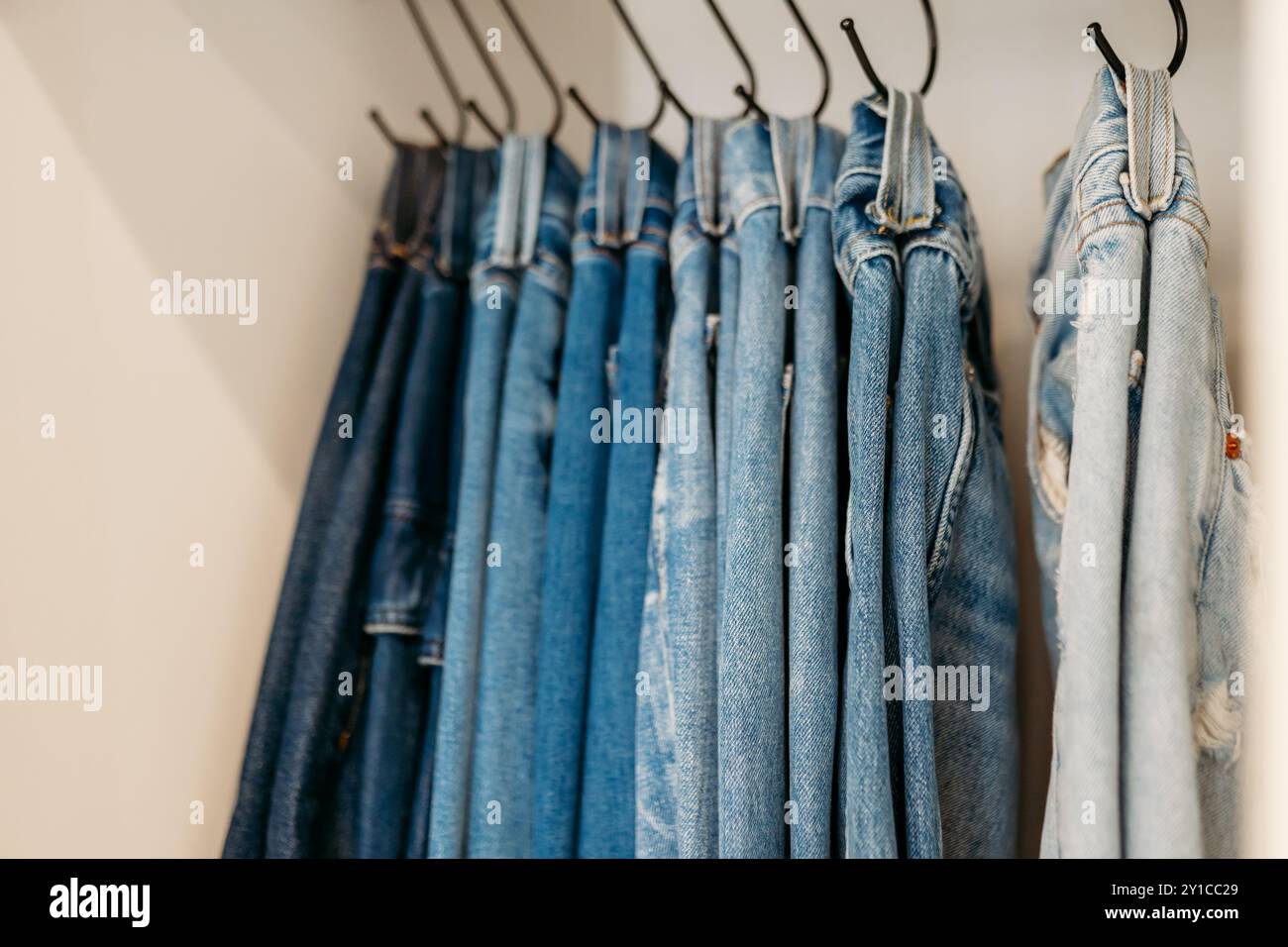 Jeans hängen an Haken, die im Schrank organisiert sind Stockfoto