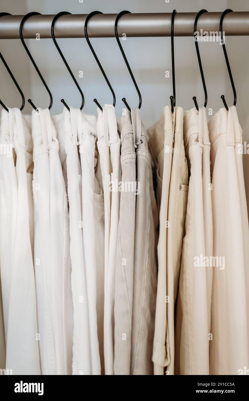Weiße und cremefarbene Jeans auf Haken im Schrank Stockfoto