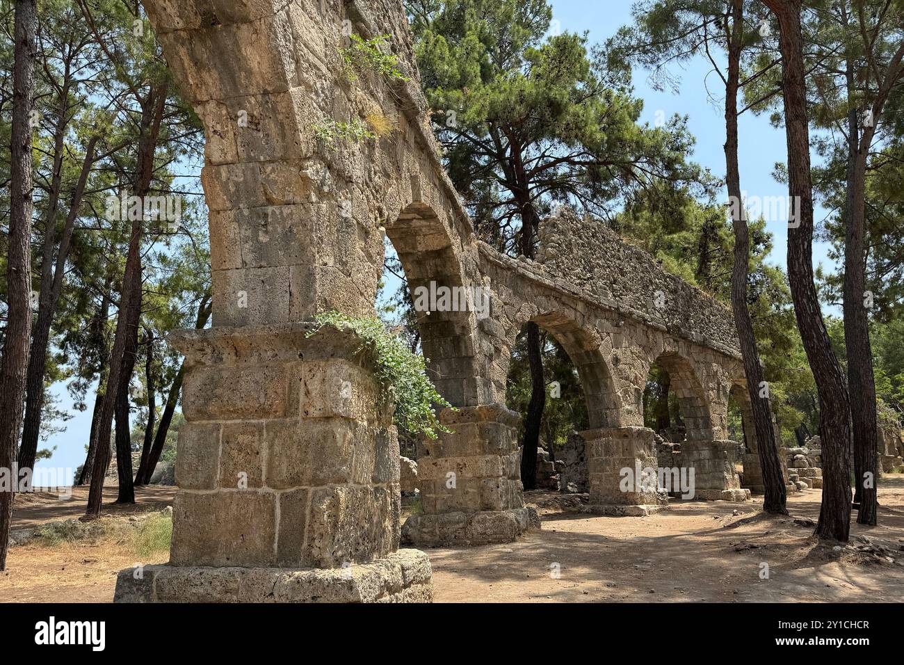 Detaillierte archäologische Ruinen des antiken römischen Aquädukts in Türkiye, Aphrodisias, Steinwasserbrücke, zweistöckige Mauer zwischen grünen Bäumen, Natur und Dörfern Stockfoto