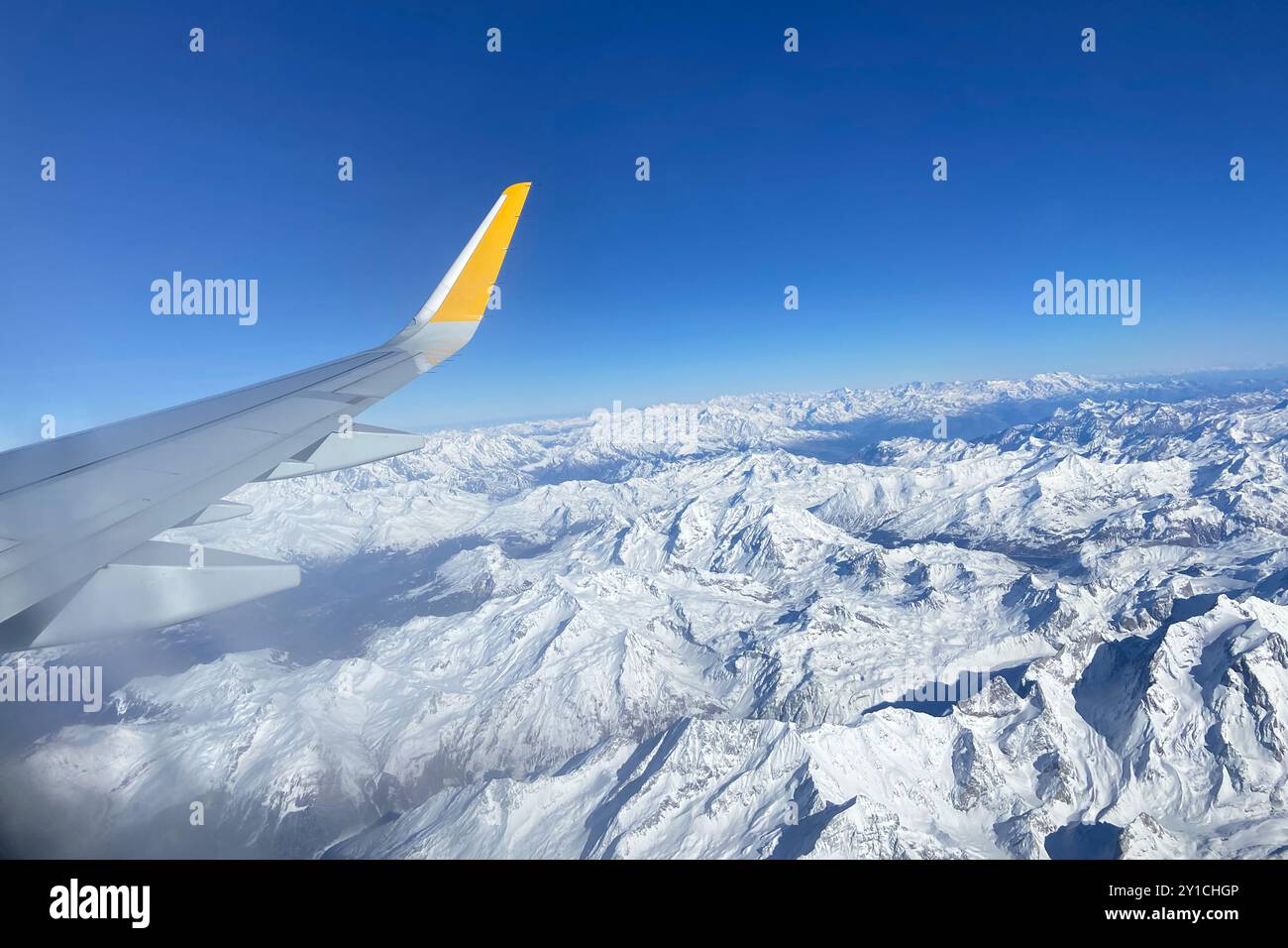 Flugzeug fliegt tief über verschneite Berge und bereitet sich auf die Landung zum Flughafen vor, Blick vom Flugzeugfenster auf die Flügelturbine und Skyline Stockfoto