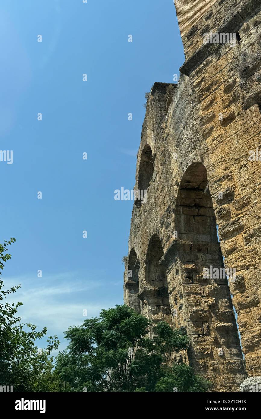 Detaillierte archäologische Ruinen des antiken römischen Aquädukts in Türkiye, Aphrodisias, Steinwasserbrücke, zweistöckige Mauer zwischen grünen Bäumen, Natur und Dörfern Stockfoto