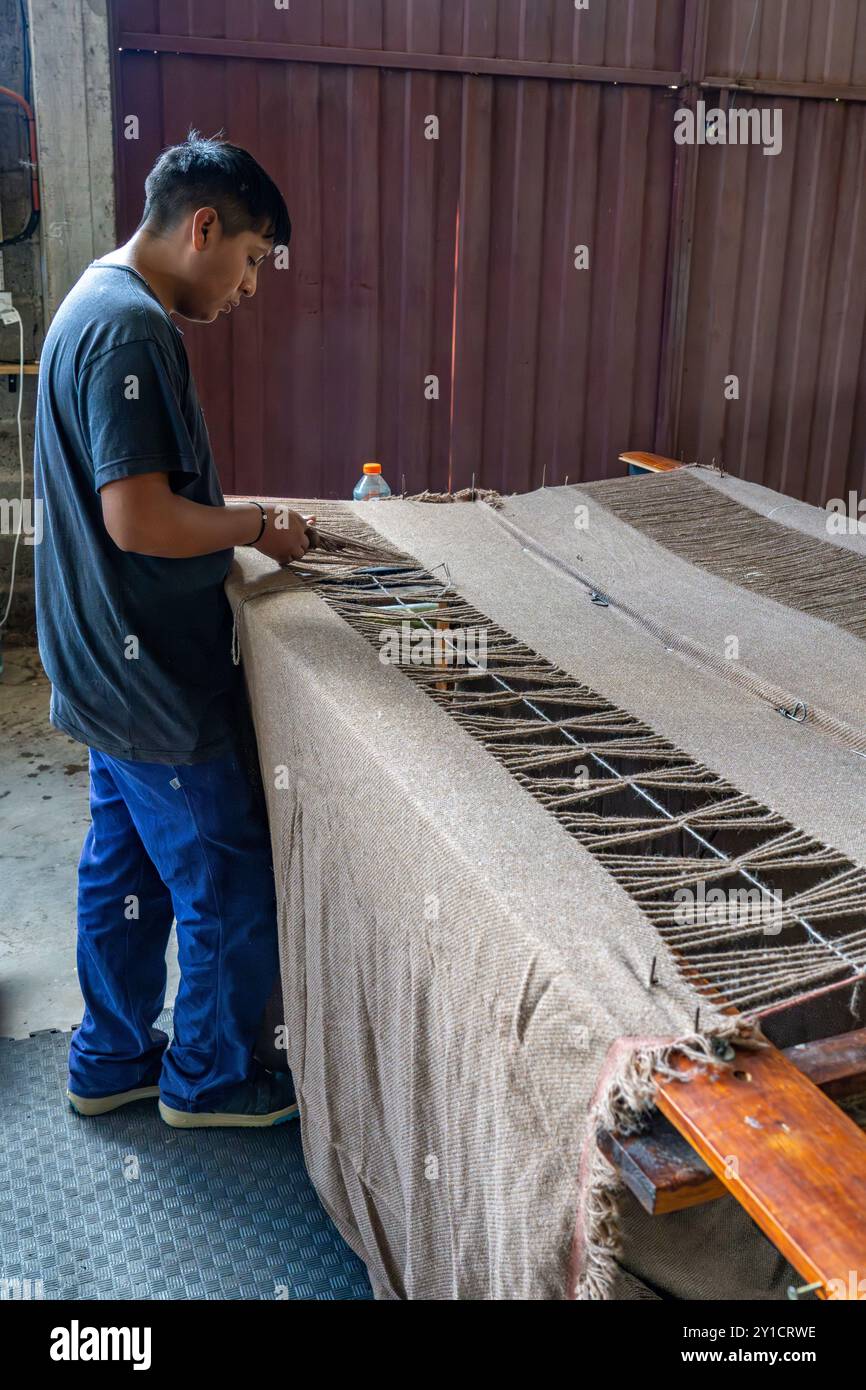 Ein Arbeiter bindet das Garn von Hand, um Quasten in Hilandería Warmi herzustellen, einer Weberei in Palpalá, Argentinien. Stockfoto