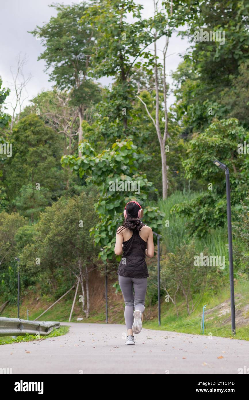 Junge asiatische Frau trägt Sport-BH und Laufschuhe, um jeden Morgen für ihre Gesundheit zu joggen, weil das Laufen ihrem Körper helfen kann, zusätzliche Energie zu verbrennen. H Stockfoto