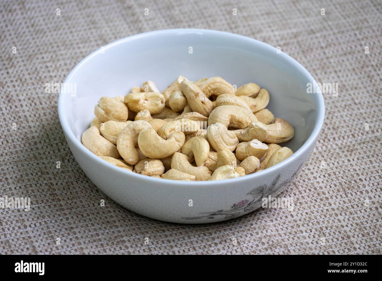 Schüssel mit Cashew-Nüssen auf einem wunderschönen strukturierten Hintergrund. Cashews sind Samen mit hohem Gehalt an Ballaststoffen, Pflanzenproteinen und herzgesunden Fetten. Stockfoto