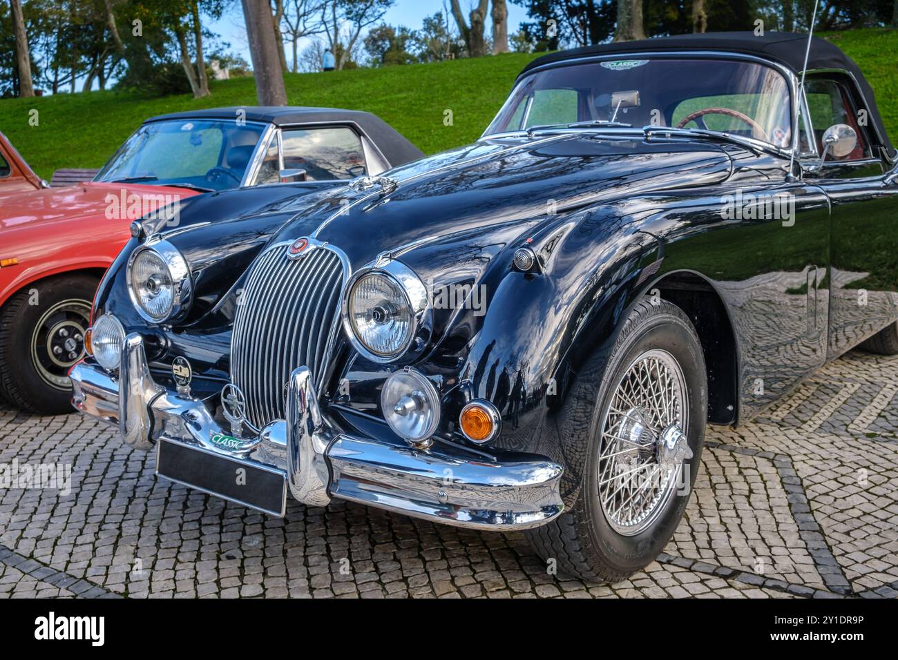 Lissabon, Portugal - 20. Januar 2024: Vintage-dunkelgrüner Jaguar XK150 Coupé mit Klappkopf auf Kopfsteinpflasterstraße parkt. Zweisitziger Roadster, Sportwagen, Cabriolet Stockfoto