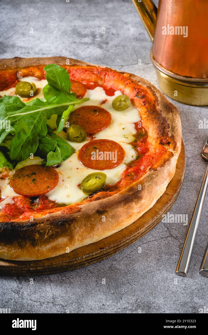 Blick von oben auf die neapolitanische Pizza mit Wurst, Jalapeno Paprika und Rucola Stockfoto