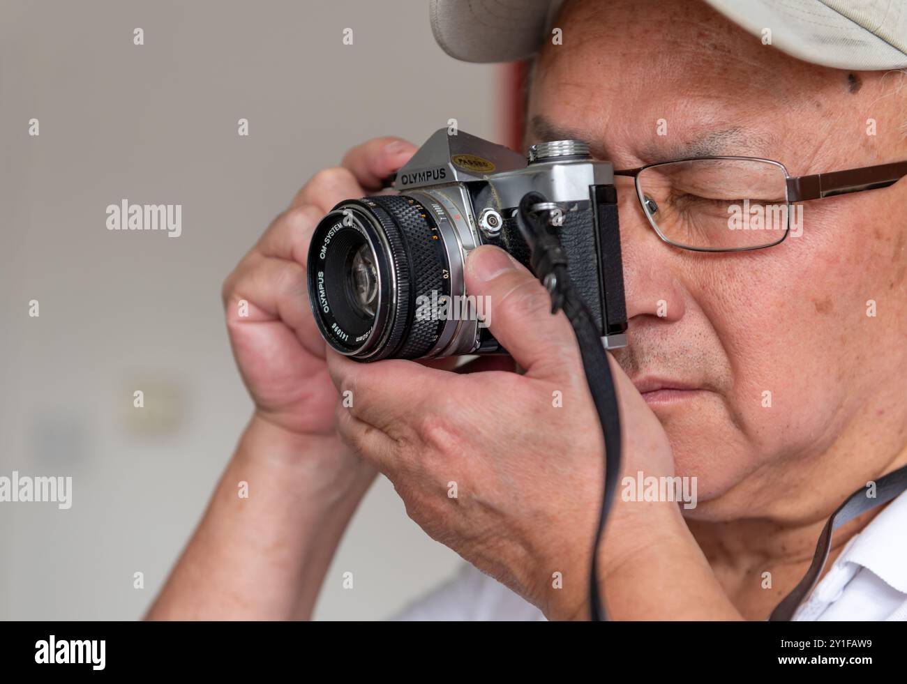 London. UK- 09.03.2024. Ein älterer Mann mit einer alten Olympus Spiegelreflexkamera. Stockfoto