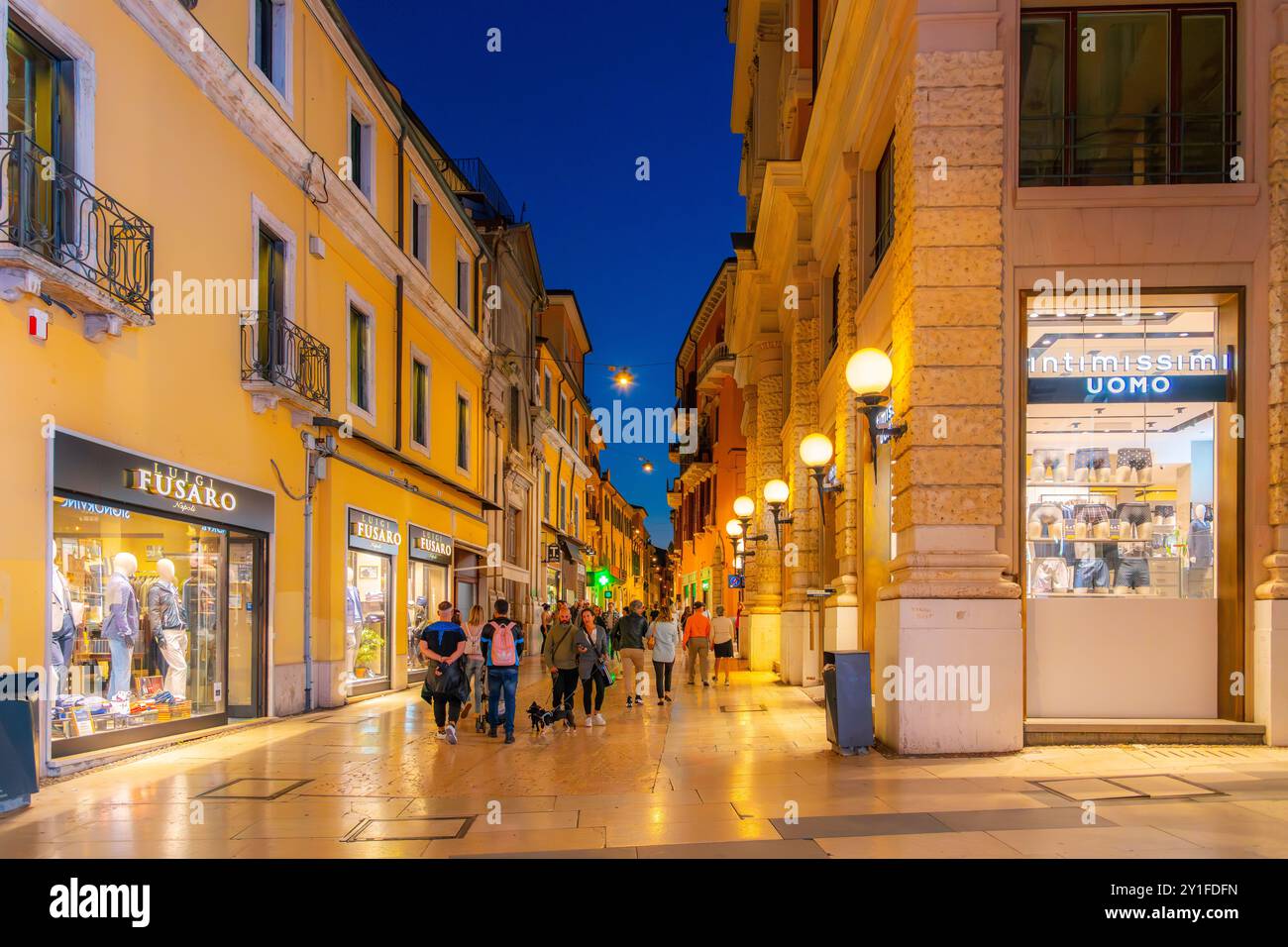 Fußgänger schlendern und besichtigen die beleuchtete Via Giuseppe Mazzini Straße mit Geschäften, Boutiquen und Cafés in der historischen Altstadt von Verona Italien. Stockfoto