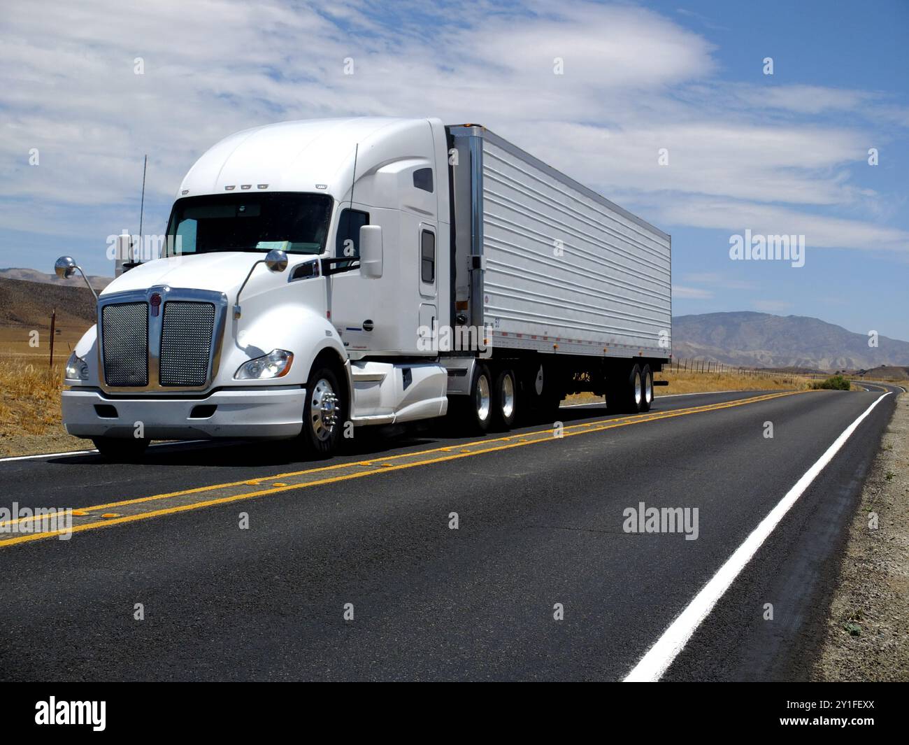 Allgemeiner weißer, großer Lkw, der in einem dramatischen Winkel auf die Kamera zusteuert, fährt auf der Autobahn Stockfoto