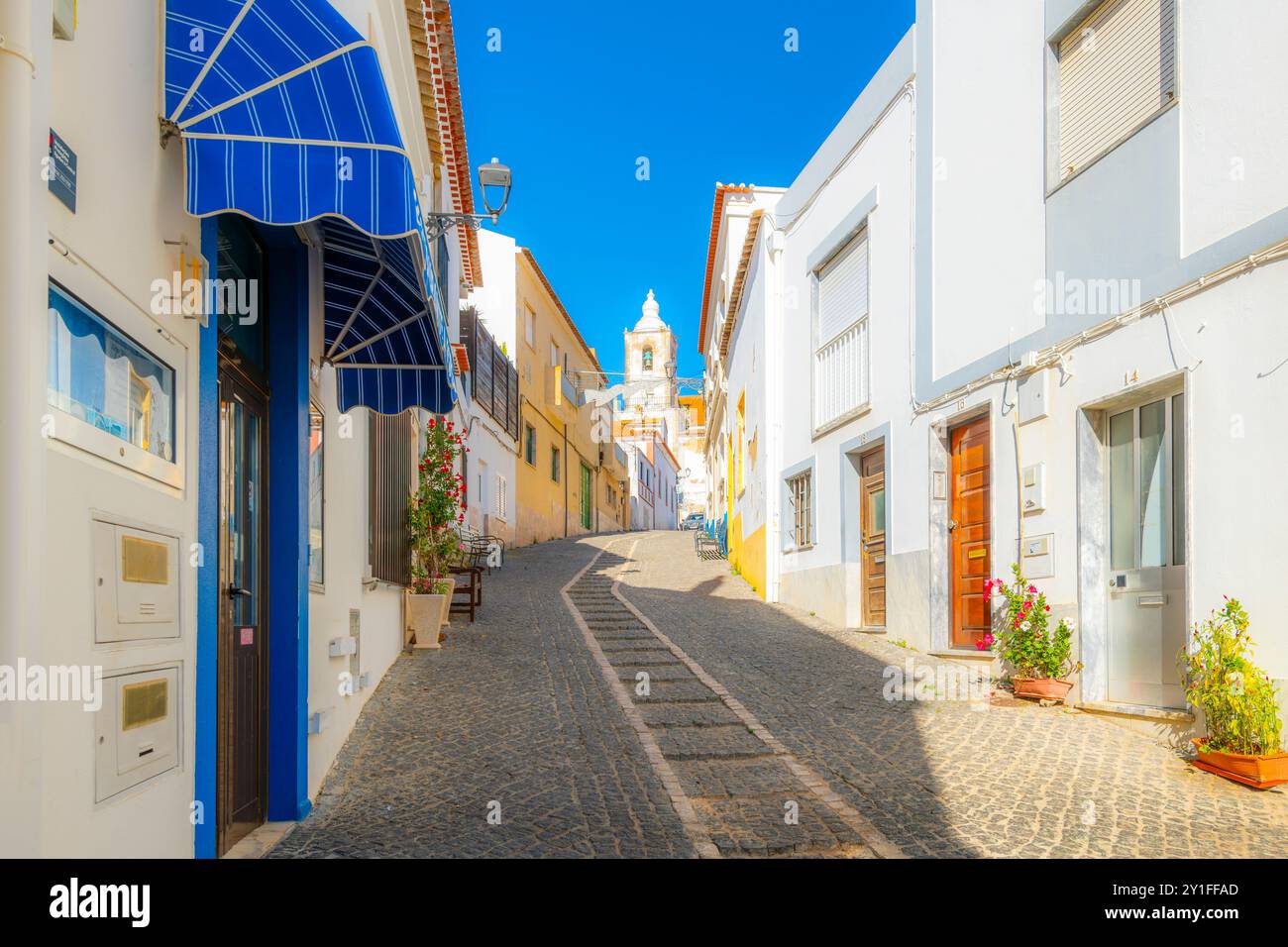 Der Glockenturm der Kirche San Sebastian aus der Kopfsteinpflasterstraße Rua dos Ferreiros in der historischen Altstadt von Lagos, Portugal. Stockfoto