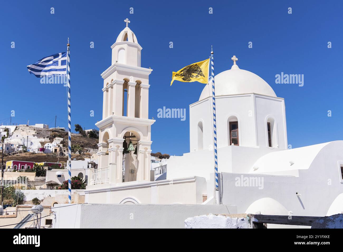 Kirche und Glockenturm in typisch griechischem Stil in Santorin mit griechischer Flagge und gelber Doppeladlerflagge in der Kirche St. Theodosias in Pyr Stockfoto