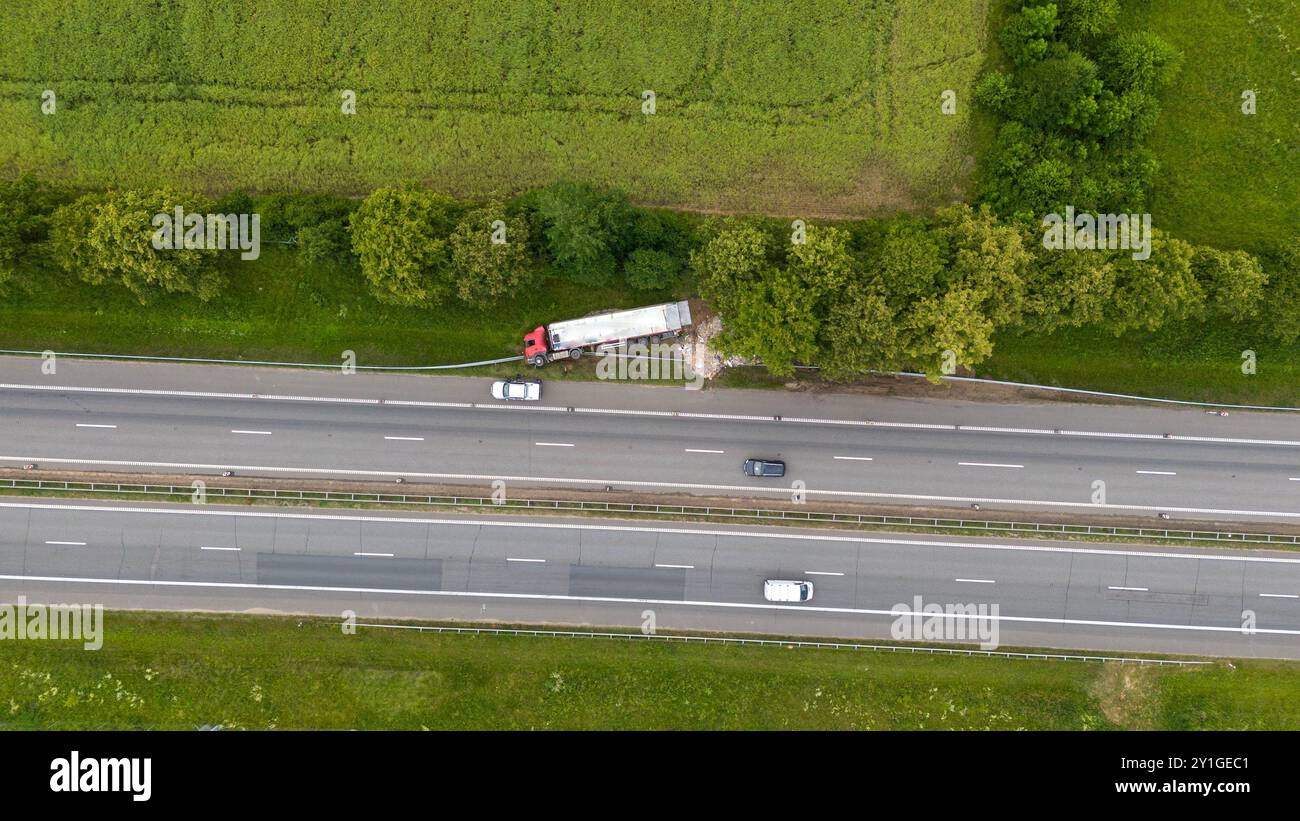 Eine Luftaufnahme eines Truck-Unfallorts auf einer Autobahn. Ein roter Truck ist von der Straße weg, in der Nähe sind Trümmer verstreut. Entlang der Konturen sind Konstruktionspegel sichtbar Stockfoto