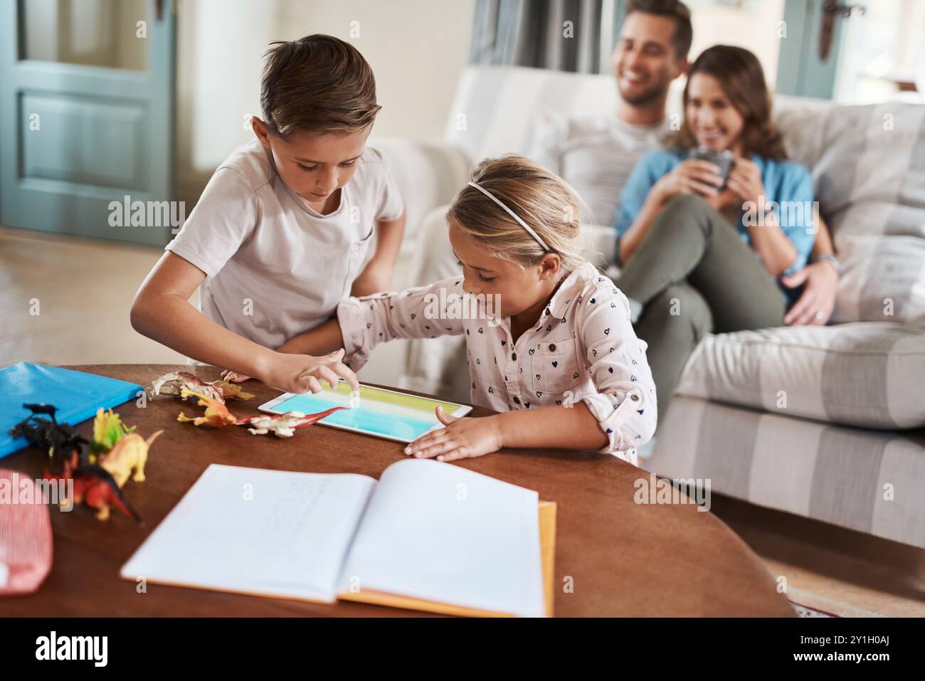 Tablet, Kinder und spielen mit Eltern auf der Couch, um sich zu verbinden, zu lernen und gemeinsam im Wohnzimmer zu entspannen. Mom, Dad und Kinder auf Sofa mit Digital Stockfoto