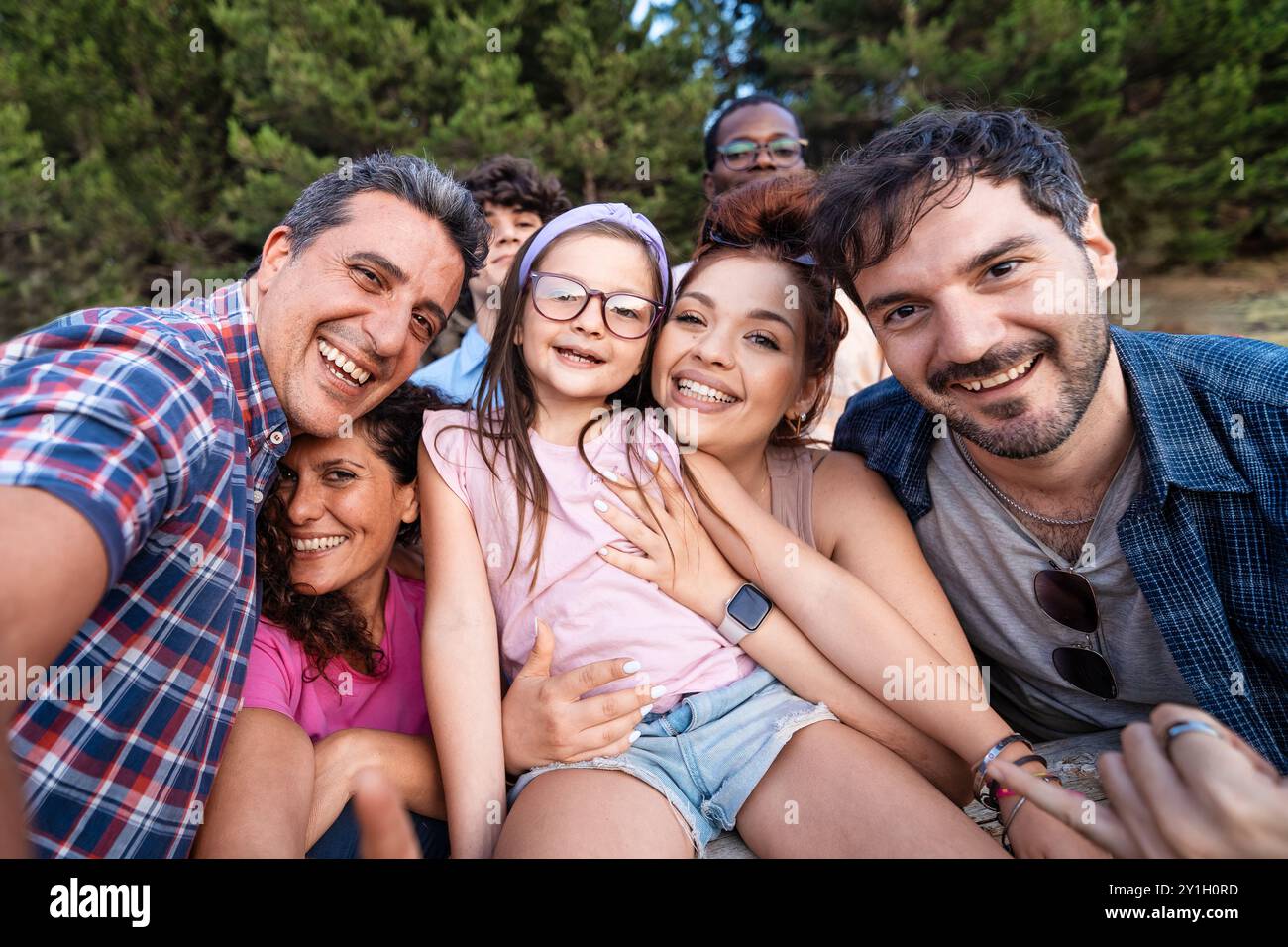 Fröhliche, generationsübergreifende Familie und Freunde machen ein Selfie in einer natürlichen Umgebung. Verschiedene Gruppen von Erwachsenen, Kindern und Senioren, die lächeln und umarmen Stockfoto