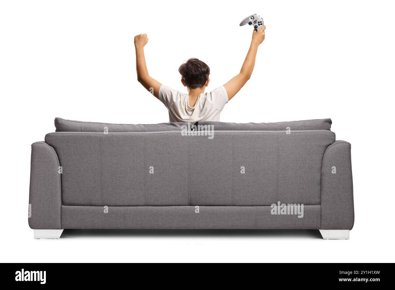 Rückansicht eines glücklichen Jungen, der auf einem Sofa sitzt und einen Joystick auf weißem Hintergrund hält Stockfoto