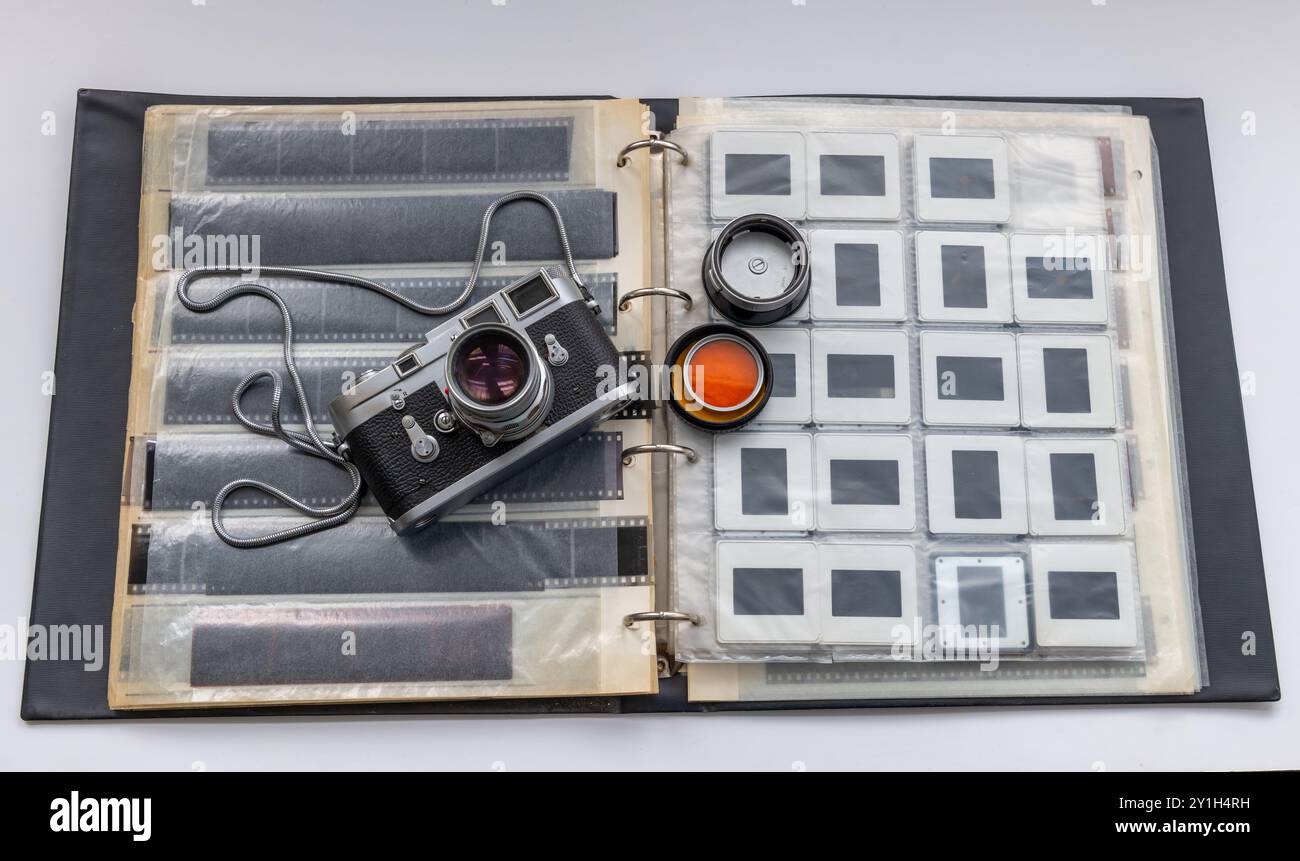 Eine klassische Vintage-Fotokamera auf einem Ordner für Dias und Negativfilme, isoliert in weiß. Stockfoto