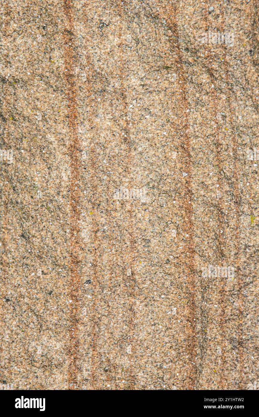 Nahaufnahme eines granulierten Gesteins. Der Fels enthält braune, rötliche Brauntöne und weiß mit vertikalen Linien. Hintergrund mit Kopierraum. Stockfoto