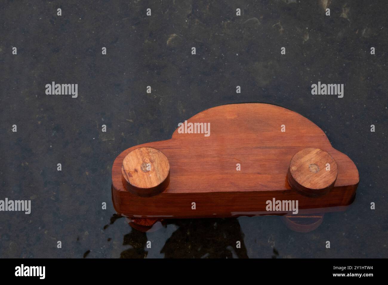 Ein hölzerner Spielzeugwagen kippte in einem See um und überflutet mit Wasser. Wird für Kfz-Versicherungen oder für Wasserschäden an Fahrzeugen verwendet. Stockfoto