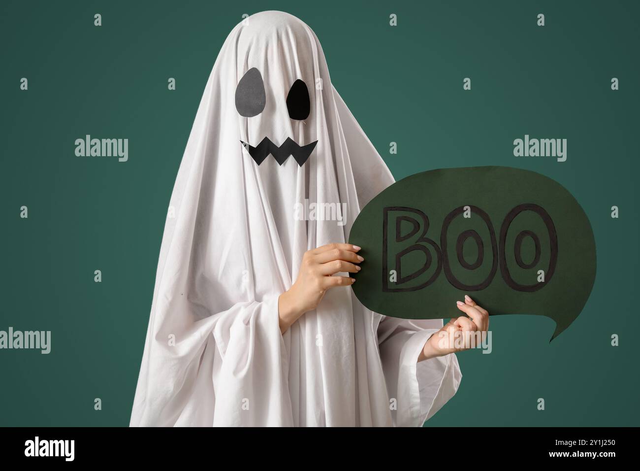 Person im Halloween-Kostüm des Geisters, der Sprechblase mit Wort BUH auf grünem Hintergrund hält Stockfoto