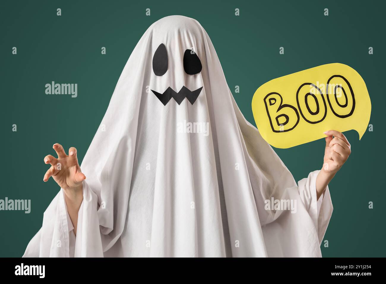 Person im Halloween-Kostüm des Geisters, der Sprechblase mit Wort BUH auf grünem Hintergrund hält Stockfoto
