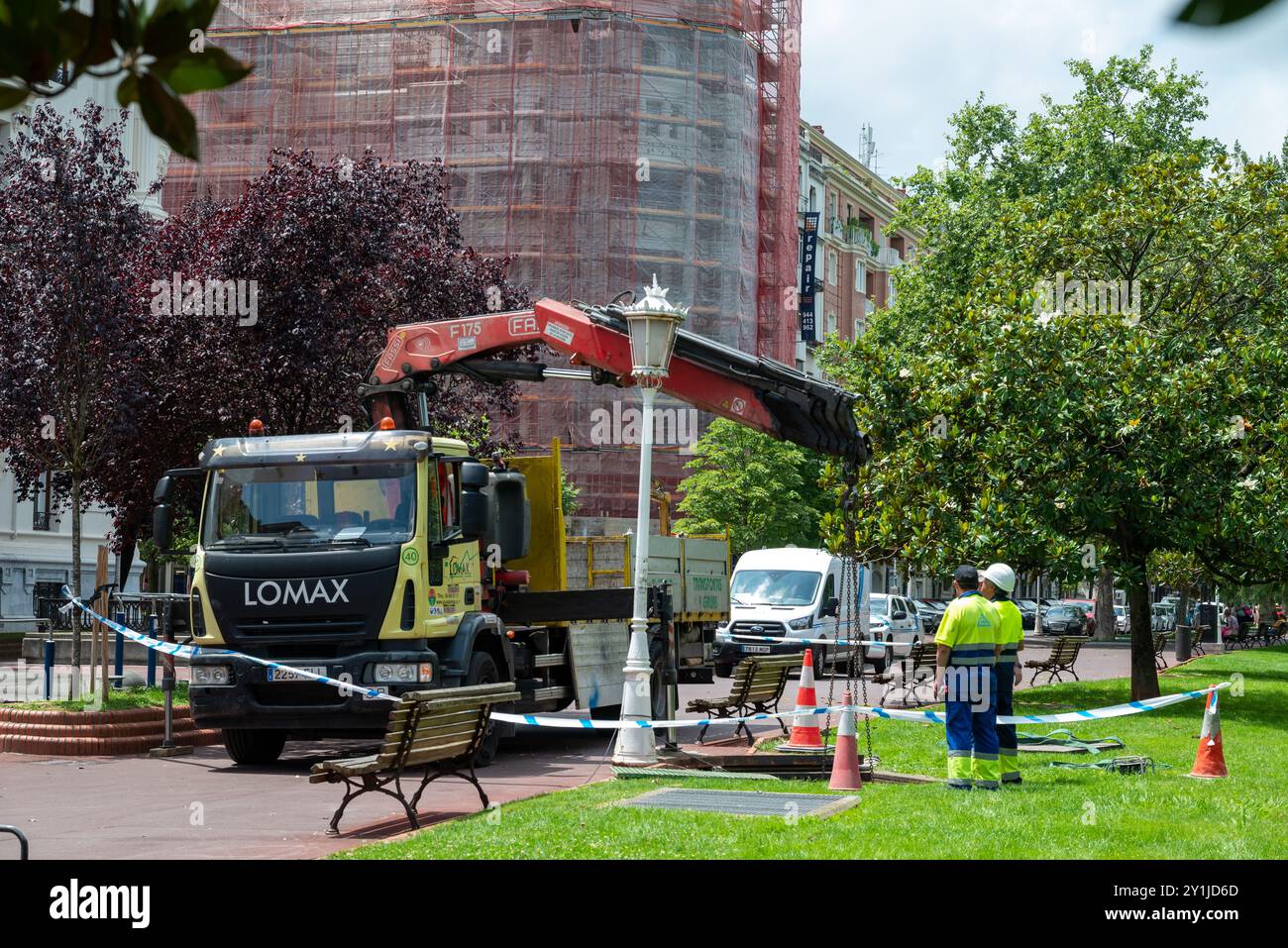 Arbeiter mit einem Kranwagen, die an einem Mannloch arbeiten. Wir befinden uns in Bilbao, in der Nähe des Hauptparks im Zentrum der spanischen Stadt. Stockfoto