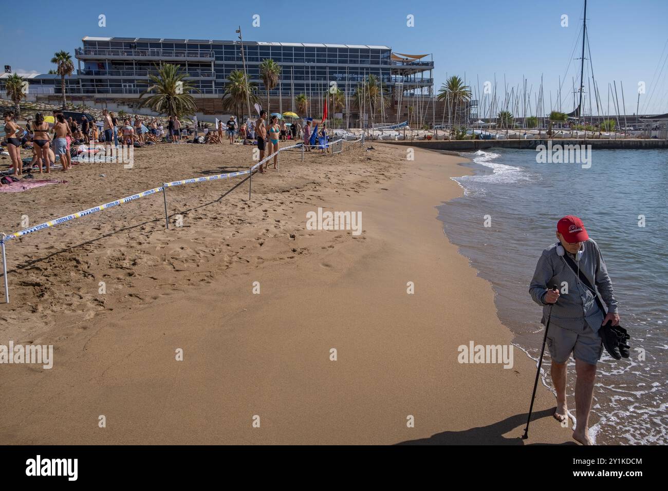 Ein älterer Mann wird am Strand entlang laufen sehen, der sich der von der Guardia Urbana erlassenen Schließung des Strandes widersetzt, um die Anwesenheit von Demonstranten im Wasser zu verhindern. Hundert Aktivisten und Einwohner Barcelonetas haben am Strand von Somorrostro in Barceloneta eine Menschenkette gebildet, um gegen die Segelveranstaltung des America's Cup zu protestieren. Nach Aussagen der Demonstranten untergräbt die Veranstaltung dieses großen Sportereignisses die Integrität der Arbeiterviertel, ignoriert Forderungen nach sofortigen Maßnahmen zur Verringerung der Tourismuswirtschaft und enteignet den öffentlichen Raum massiv von den konfessionen Stockfoto