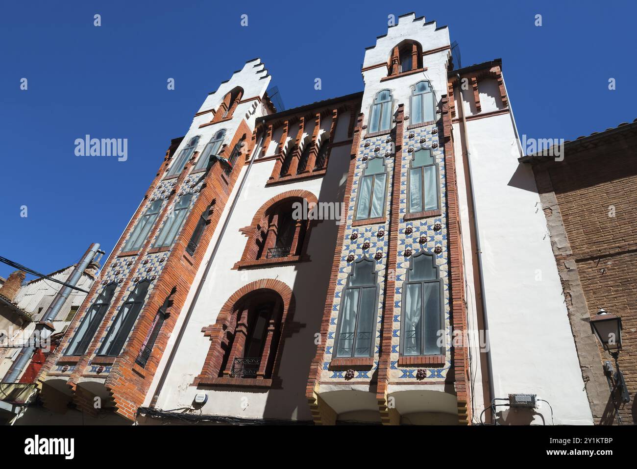 Ein beeindruckendes Gebäude mit einer kunstvollen Ziegelfassade und wunderschönen Fenstern unter einem klaren blauen Himmel, modernistisches Haus, Moderne, Estudios Straße, Sori Stockfoto