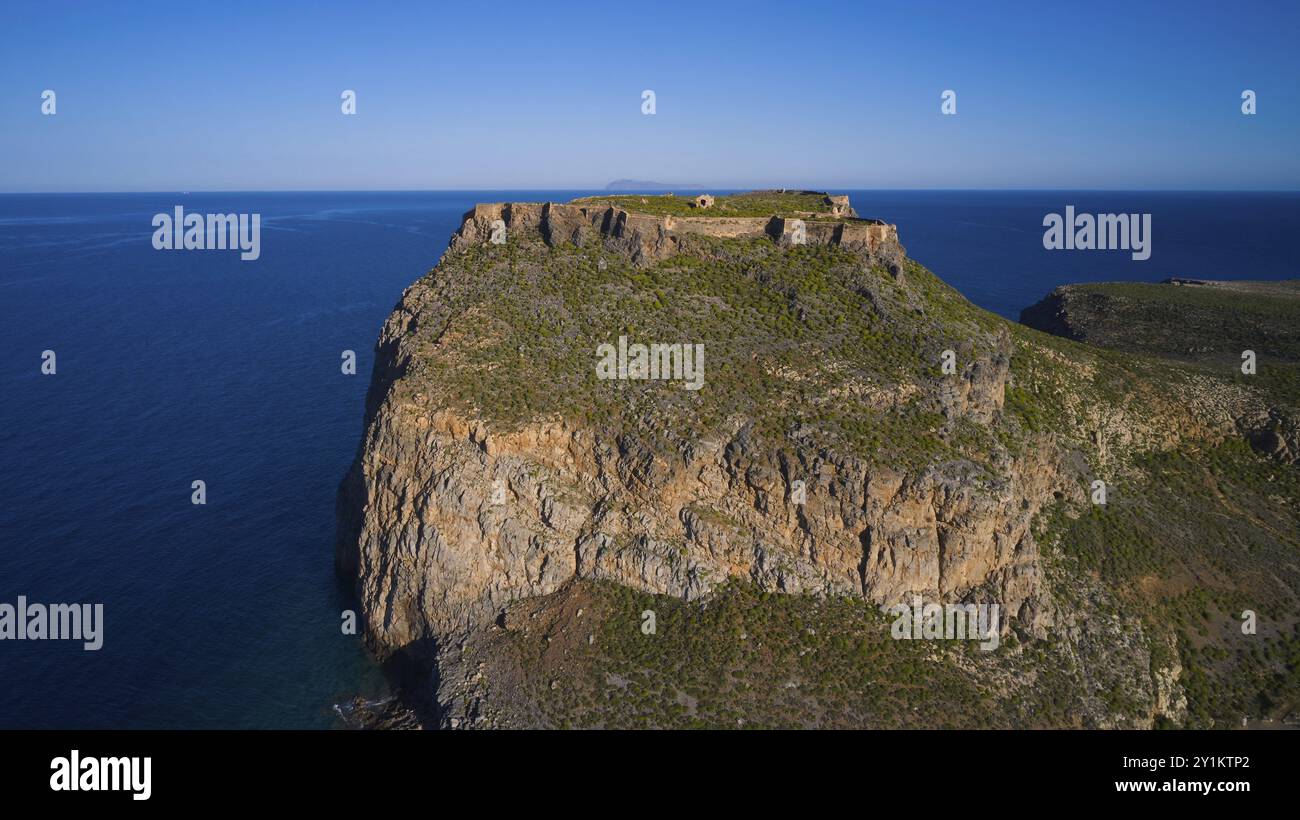 Drohnenaufnahme, Eine dramatische, felsige Küste ragt ins blaue Meer mit üppiger Vegetation auf den Klippen, Venezianische Meeresfestung, Gramvoussa, Gramvoussa Penin Stockfoto