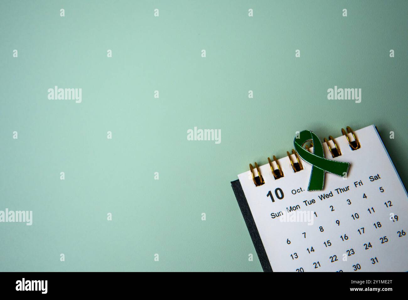 Ein Kalender öffnete sich bis Oktober und ein grünes Band, das das Bewusstsein für psychische Gesundheit symbolisiert. Kopierbereich für Text. Stockfoto